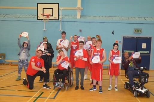 A group of basketball players in red uniforms holding up certificates