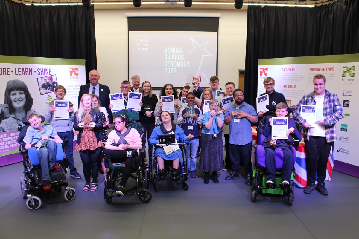 A group of learners smiling at the camera holding certificates or a glass award trophy