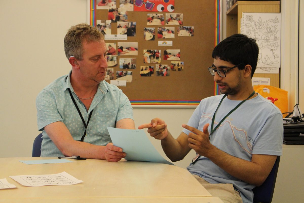 Learner and tutor talking about and pointing to some work