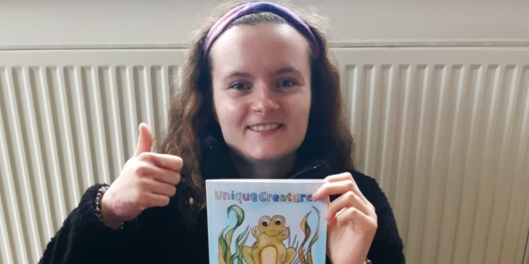 Learner holding her newly published Unique Creatures Book with frog front cover