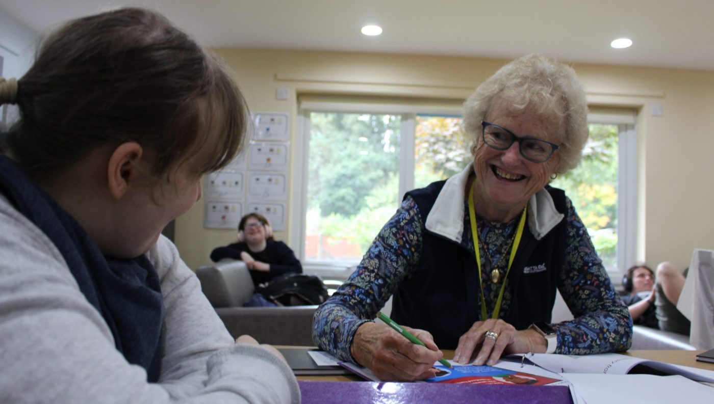 Image of a volunteer smiling at a learner in a classroom