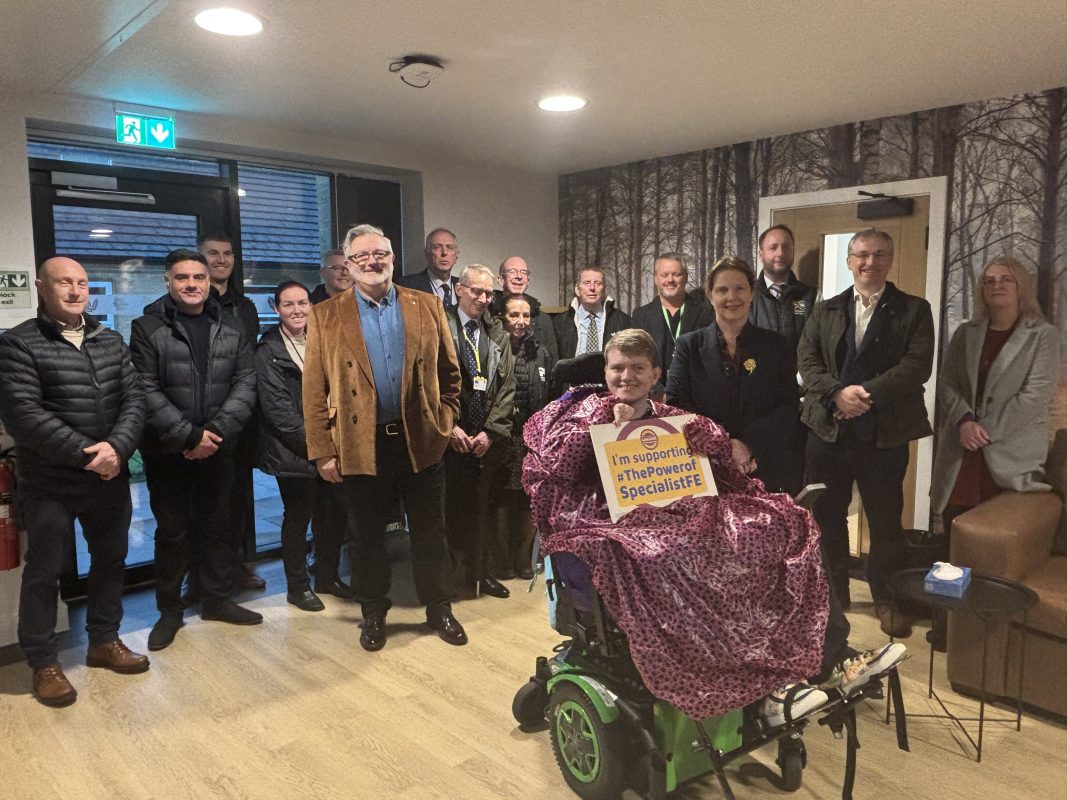 A group of men and women with a wheelchair user at the front, looking at the camera and smiling at the launch of the Pines residential building.