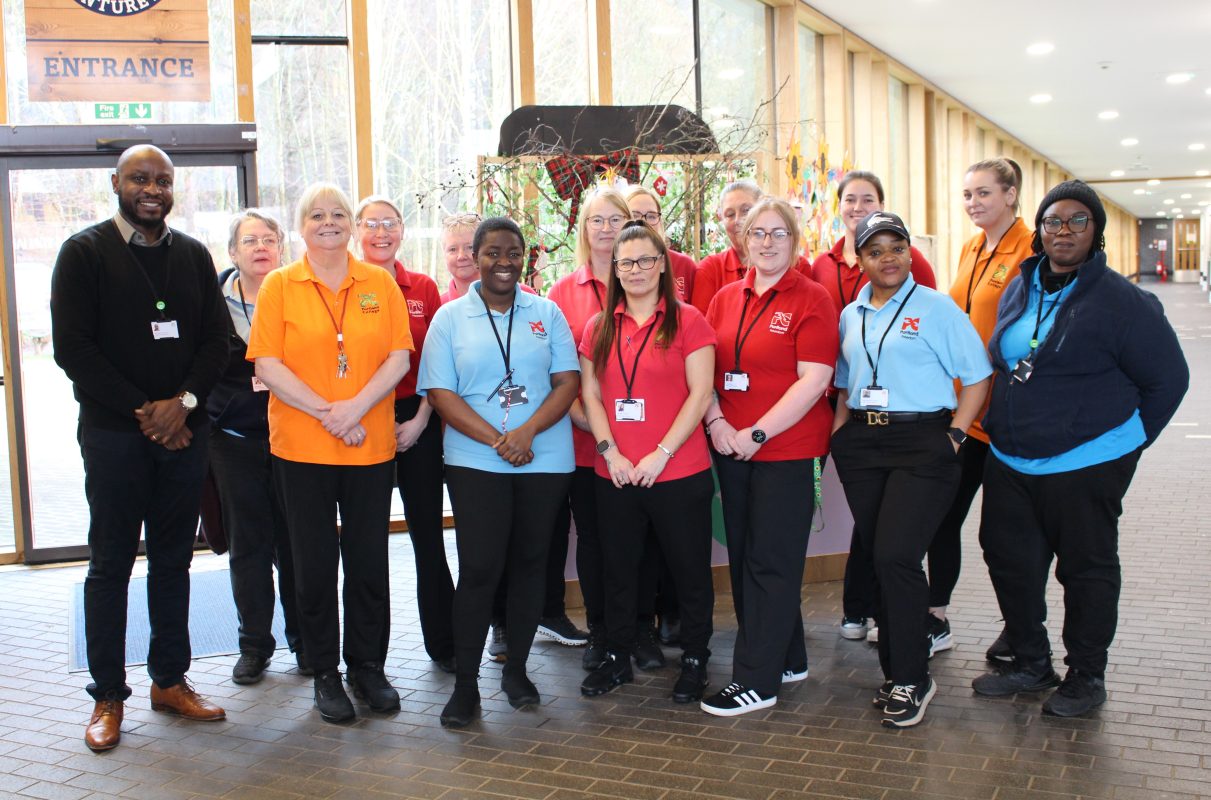 fifteen members of staff wearing orange, red and blue branded polo shirts, smiling