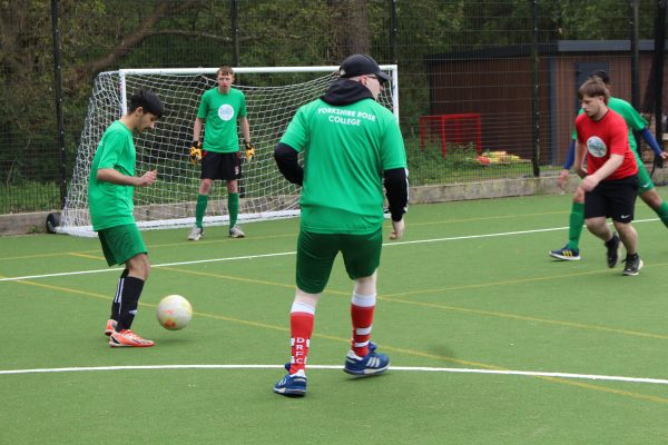 a group of young boys playing football wearing green and red tops to show opposite teams