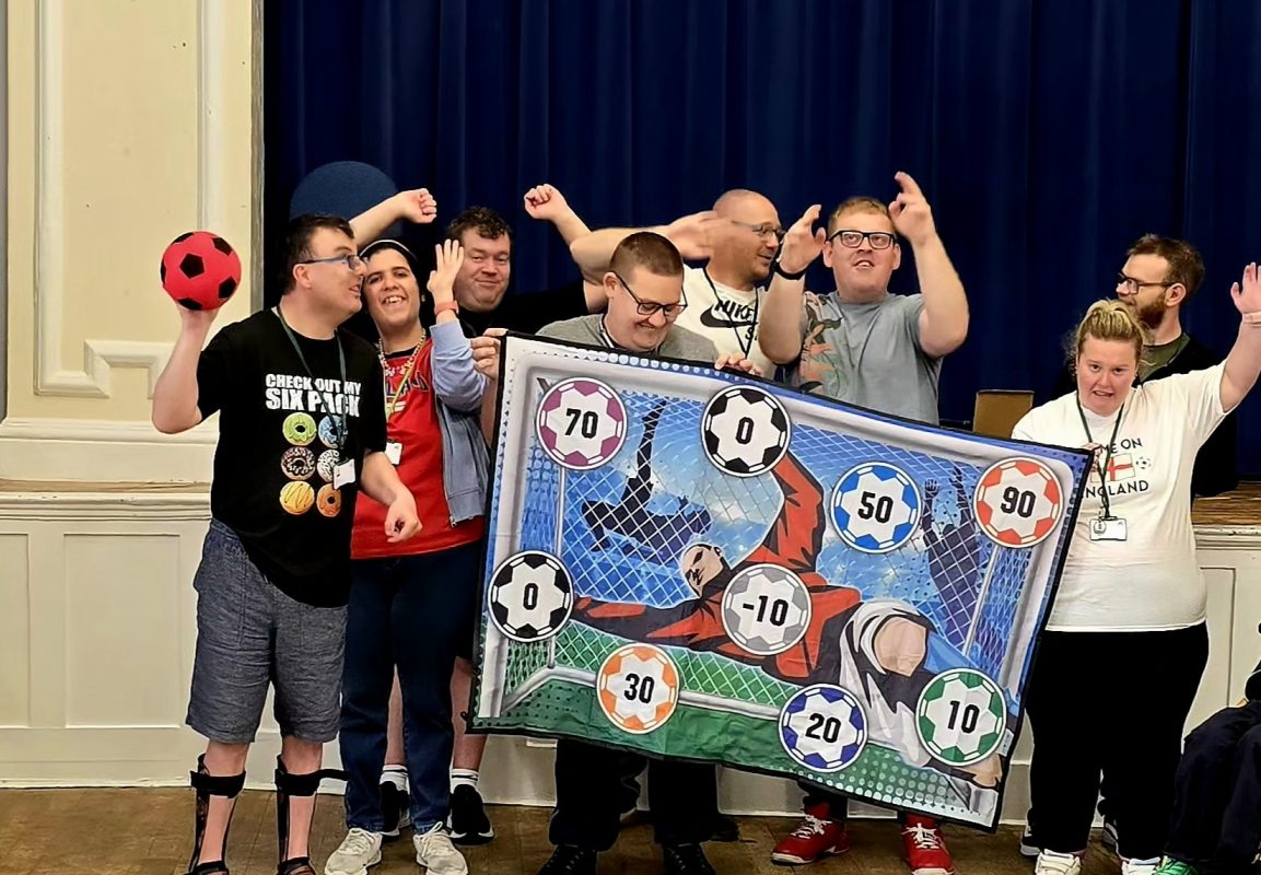 A group of boys and girls holding up a football themed banner