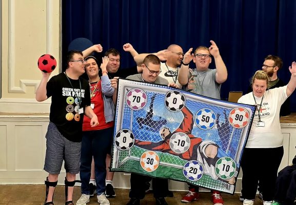 A group of boys and girls holding up a football themed banner