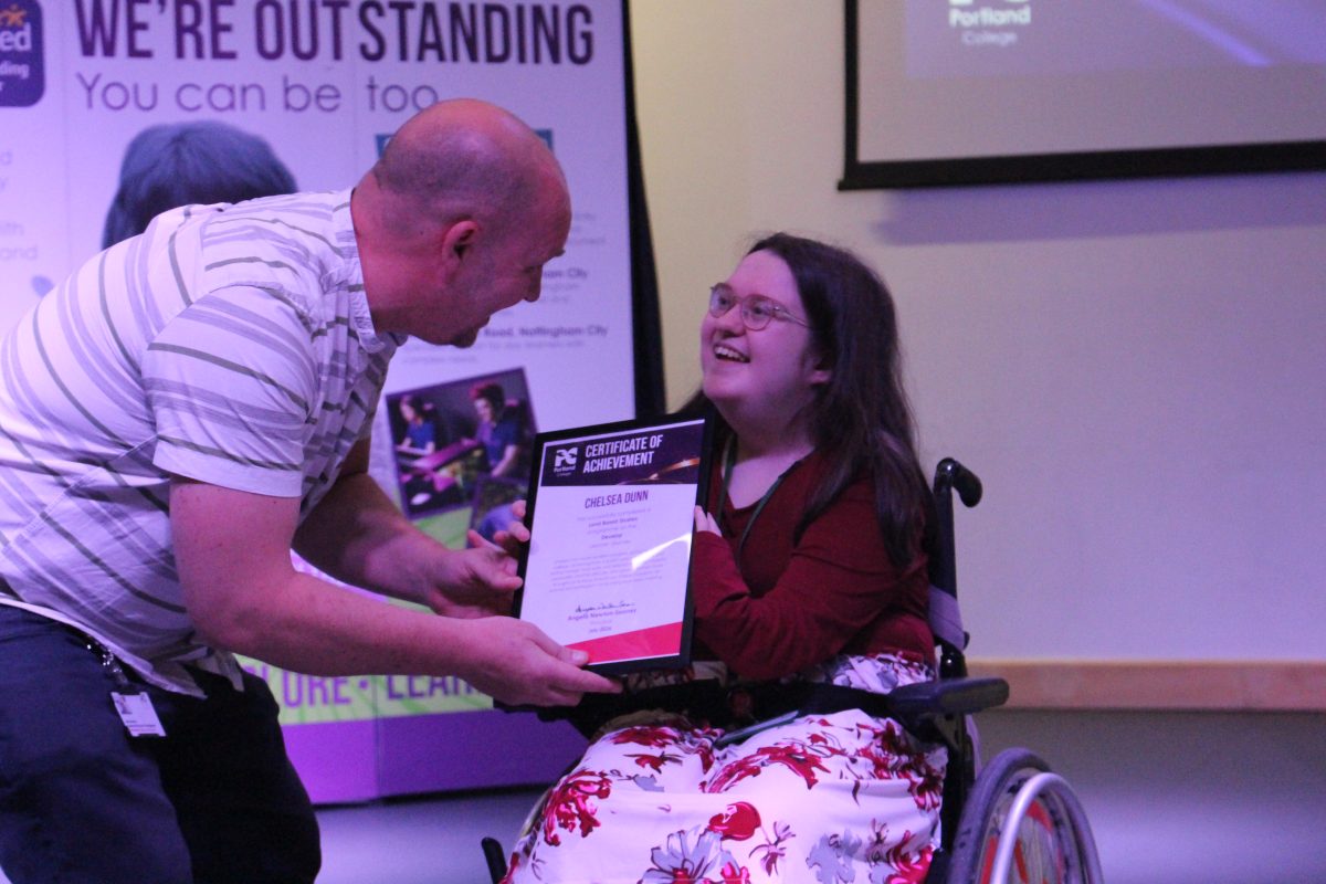 Assistant Principal Mark Morton hands learner Chelsea who is in a wheelchair with her graduation certificate