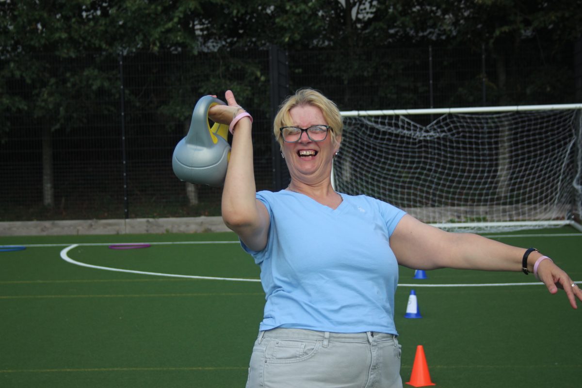Female citizen wearing a blue top, carrying a grey kettlebell.