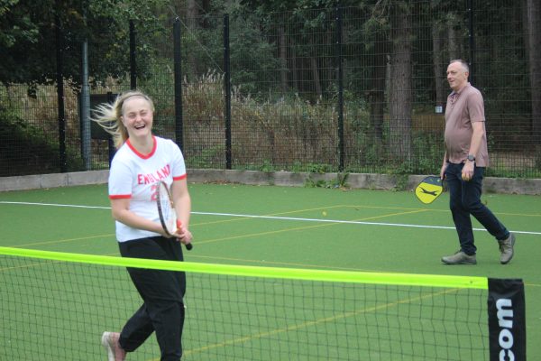 Female learner and male mentor playing tennis