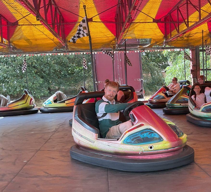 Citizen wearing a green sweatshirt smiling while driving a bumper car
